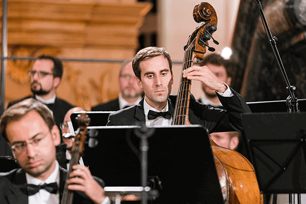 Ein Mann, der auf einem Kontrabass spielt, begleitet von einem Orchester